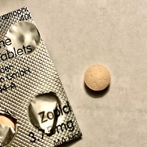 One orange zopiclone tablet next to part of a pack of zopiclone.